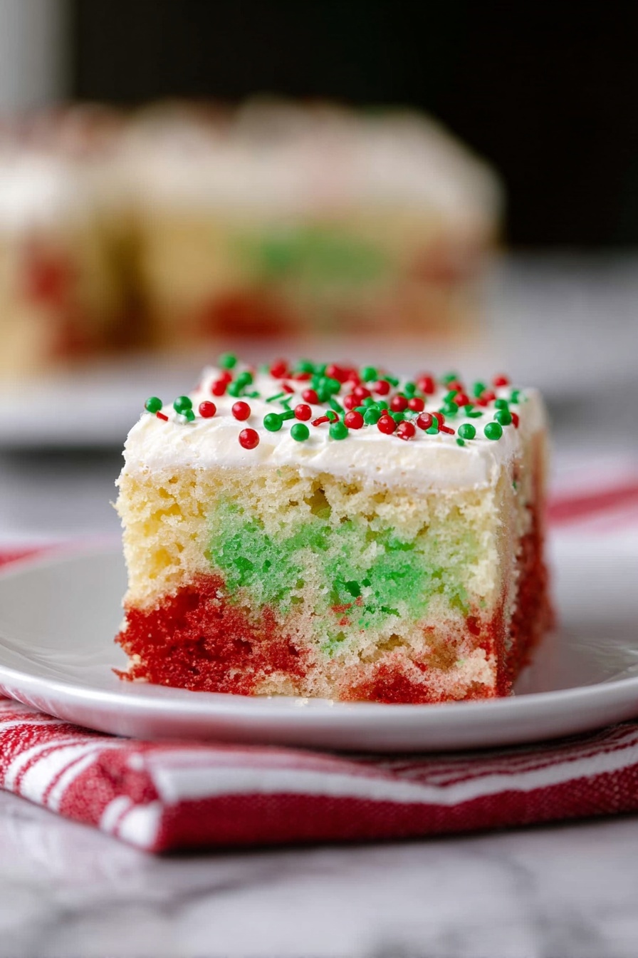 A square slice of cake with two visible layers sits on a white plate over a red and white striped cloth, set against a white marbled surface. The bottom layer is thick with a light, fluffy texture, showing a color mix of green on the left and red on the right with small holes throughout. The top layer is a smooth, creamy white frosting, evenly spread and topped with small red and green round sprinkles. The background is softly blurred to emphasize the cake in the front. Photo taken with an iphone --ar 2:3 --v 7